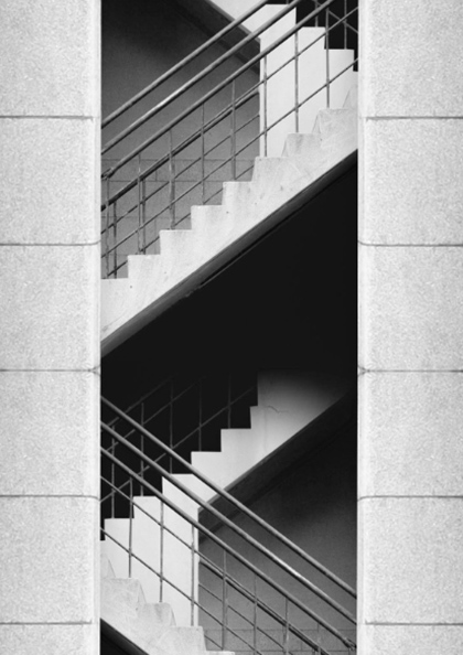A black and white photo of stairs going up the side of a building.