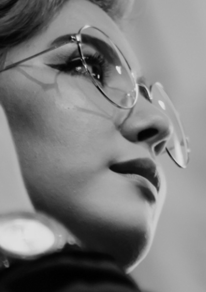 A woman wearing glasses and looking to the side.